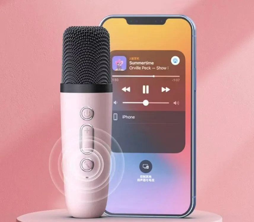 Pink portable Bluetooth karaoke speaker with microphone and coloured lights on a desk.