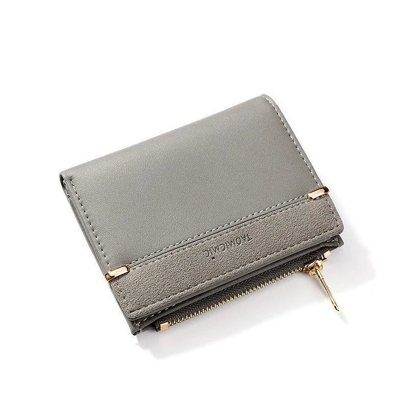 Black ladies folding wallet with a short zip, open to show multiple card slots, bill holder, and change compartment.