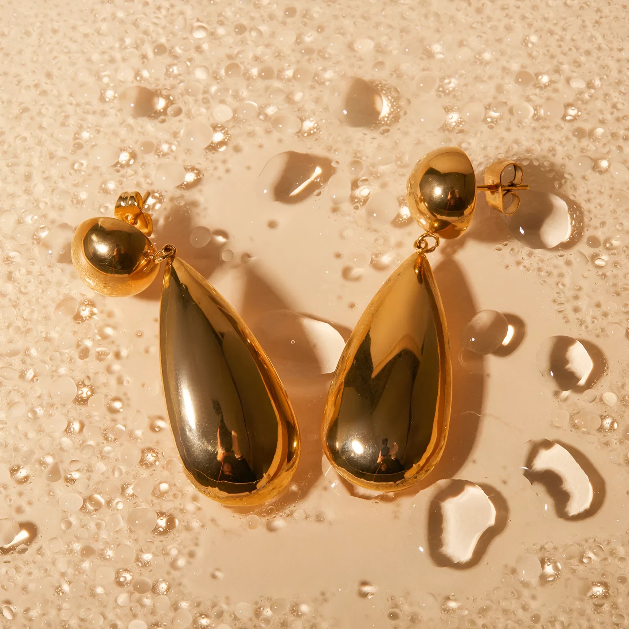 Gold-coloured stainless steel earrings with geometric water drop hemisphere pendant design