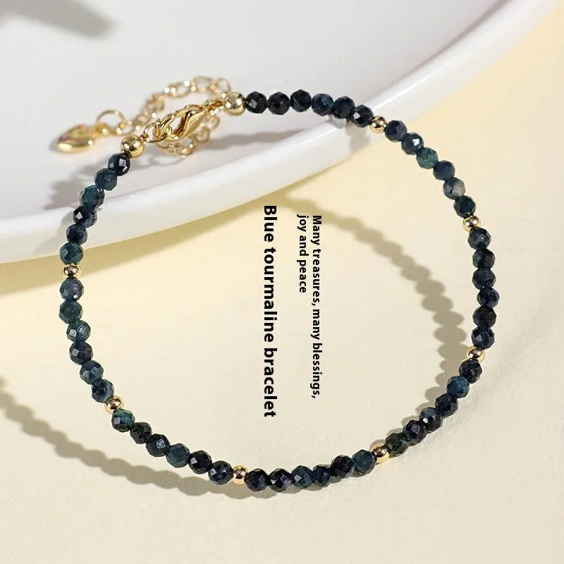 Close-up of a women's blue tourmaline gemstone beaded bracelet with 3mm beads and spacer design.