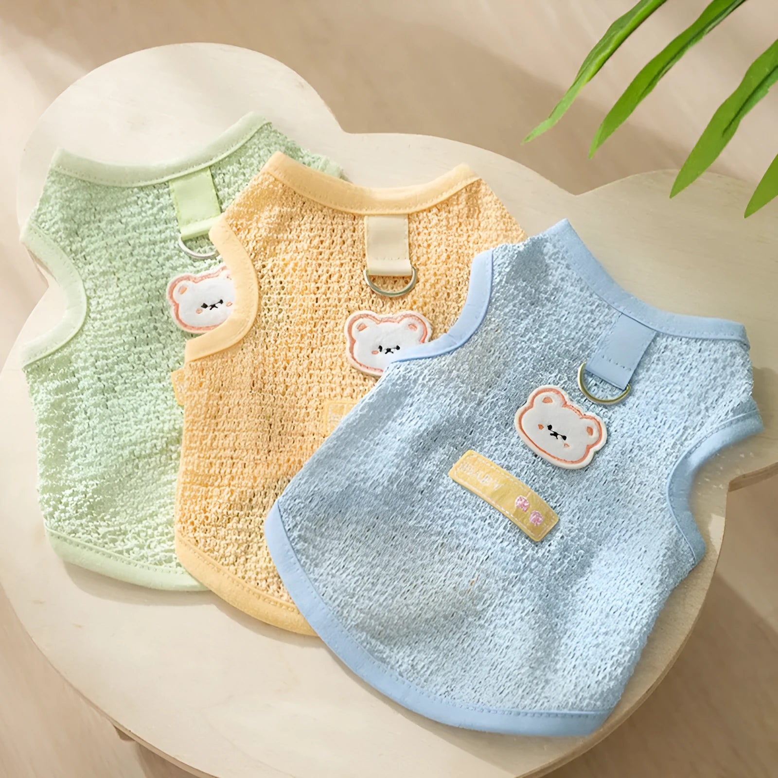 Green knitted cat clothing with a bear patch, showing hollowed-out breathable knit fabric.