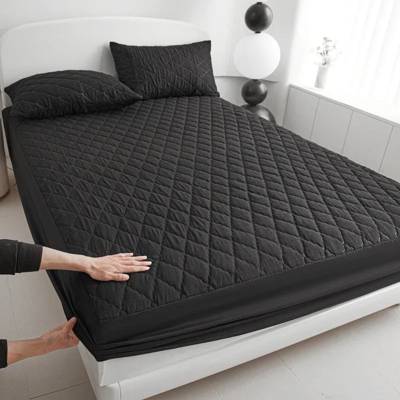 Diamond lattice quilted waterproof mattress protector fitted sheet in a solid colour on a bed.