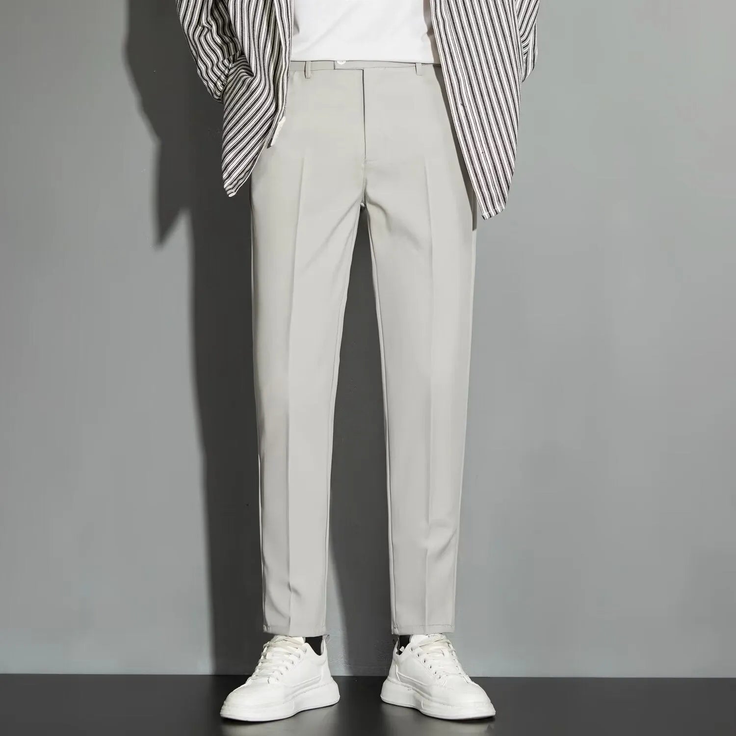 Man wearing straight-leg suit trousers with an ankle-length draping effect in a light colour.