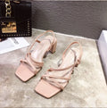 Women's white thick heel sandals with a backless design and side cut-outs on a wooden floor.