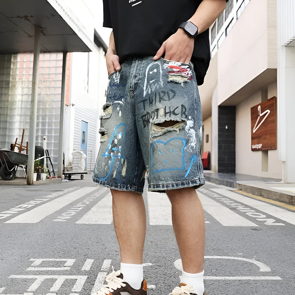 Blue ripped men's denim shorts with graffiti detail and a straight leg.