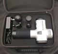 Black fascia massage gun with four different coloured massage heads on a grey background.