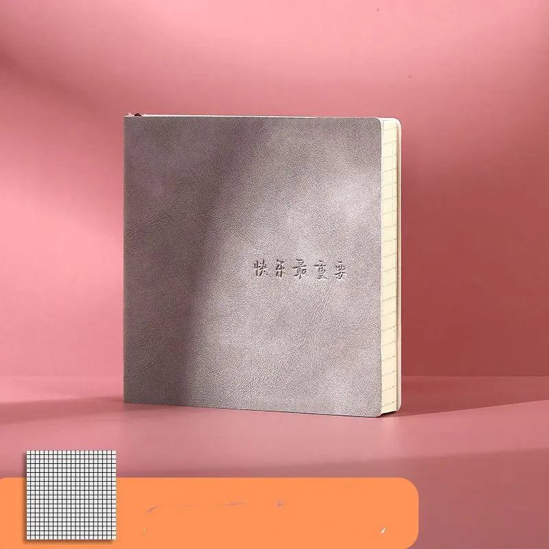 Square notebook with textured faux leather cover showing French fold binding and open blank pages
