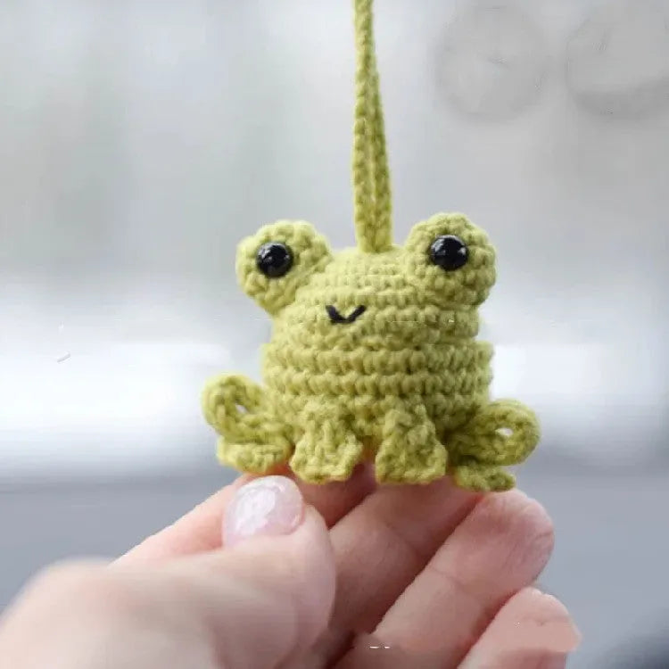 Handmade woven car pendant with a green frog plush doll hanging.
