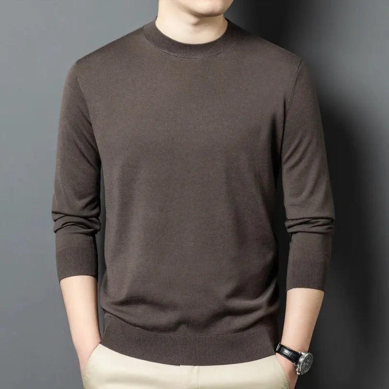 Man wearing a round neck grey wool blend sweater with long sleeves.