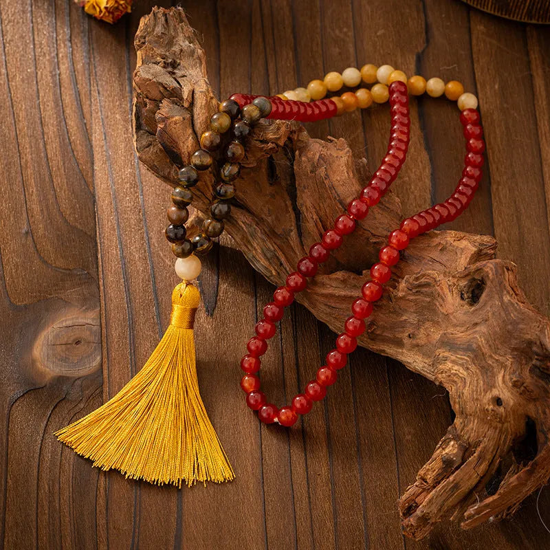 Long natural stone beaded sweater chain necklace and matching bracelet in bohemian style on a grey background.