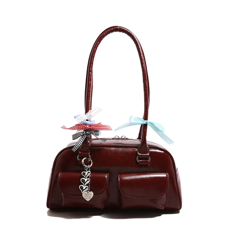Retro women's black PU leather pillow-shaped shoulder bag with flap and double straps, shown with optional ribbon pendant.