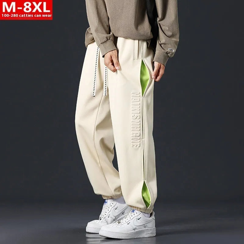 Men's loose grey green cotton trousers with ankle banding and stitching print detail on the leg.