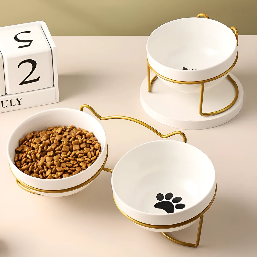 White ceramic pet bowl with cat paw design on a black metal stand with cat ear details.