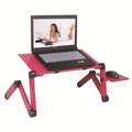 Black metal folding computer desk with cooling fan, extended on a bed.