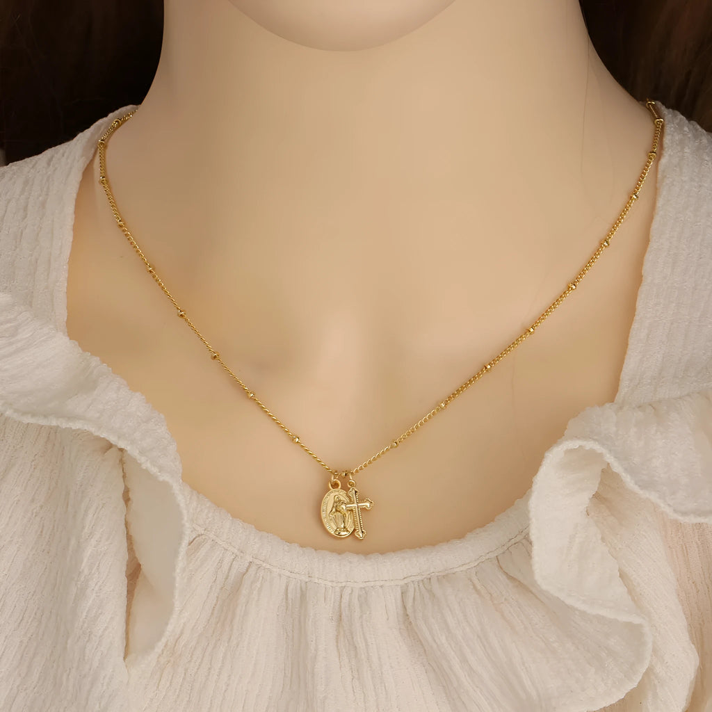 Gold Virgin Mary and cross geometric pendant necklace on a simple chain.