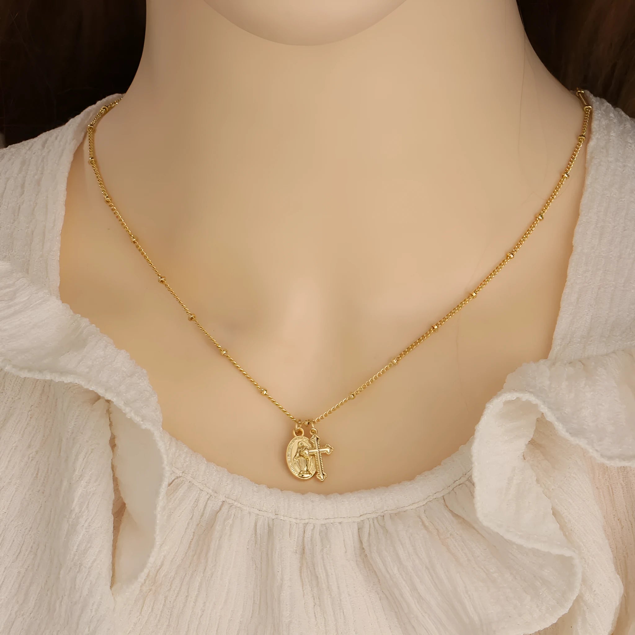 Gold Virgin Mary and cross geometric pendant necklace on a simple chain.