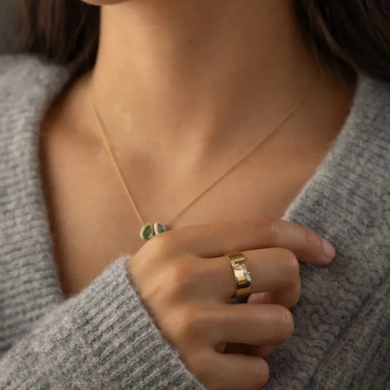 Gold-coloured copper ring with a shining zircon stone on a model's hand.