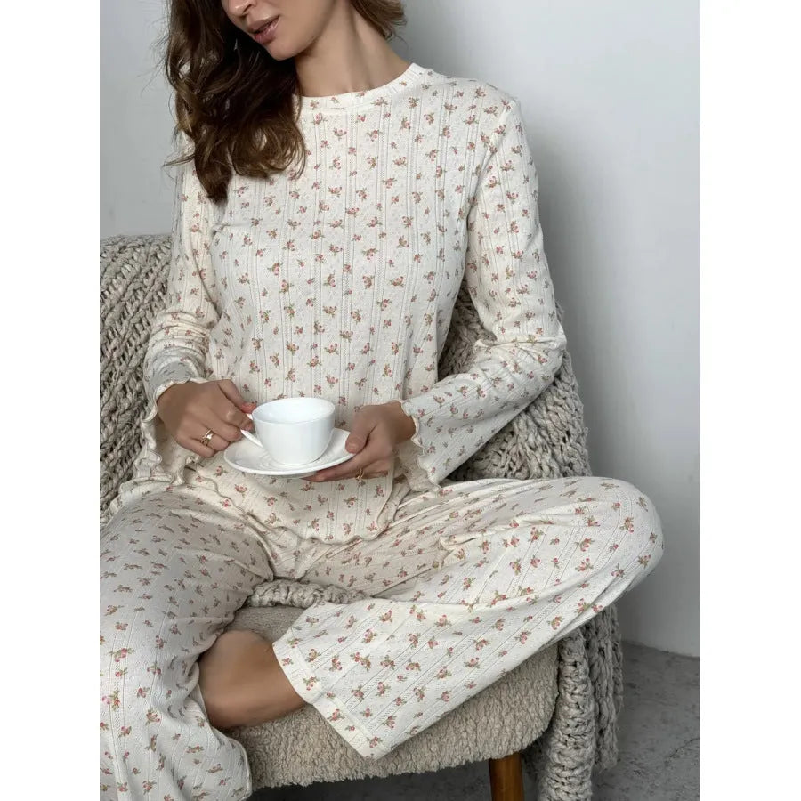White floral print women's two-piece suit with bell sleeve top and wide leg trousers laid flat.