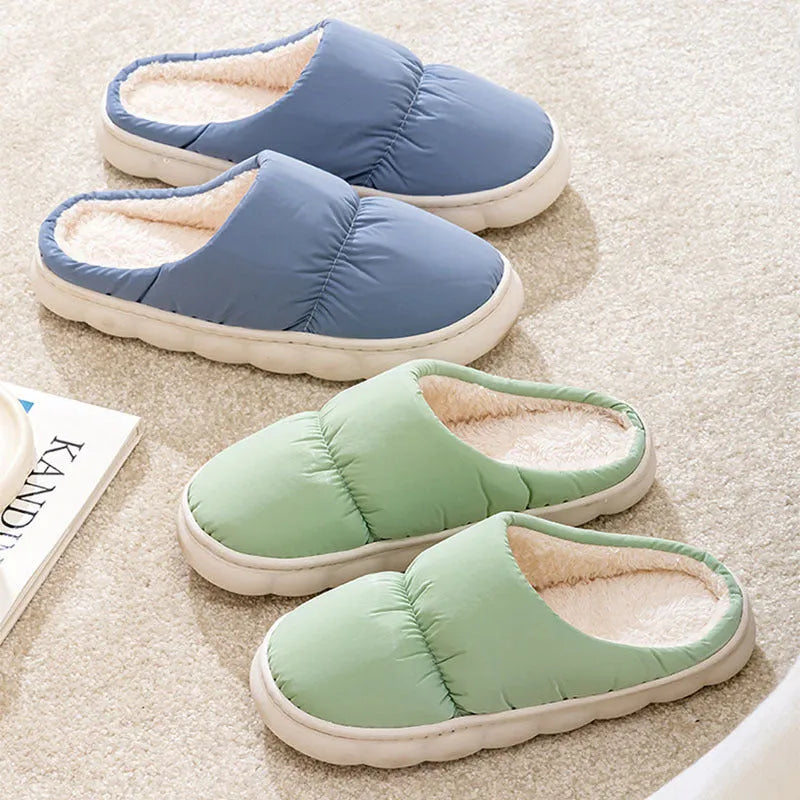Blue down cotton indoor slippers with thick rubber sole and plush lining, shown on a wooden floor.