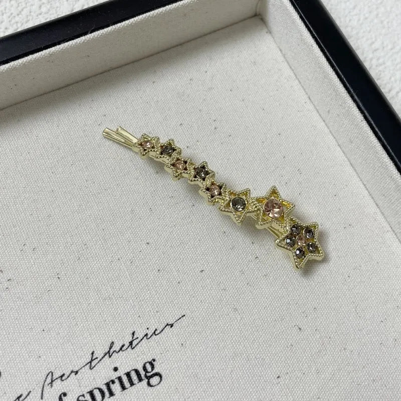 Gold alloy hair barrette with rhinestones and a star charm, shown as a side clip for bangs.