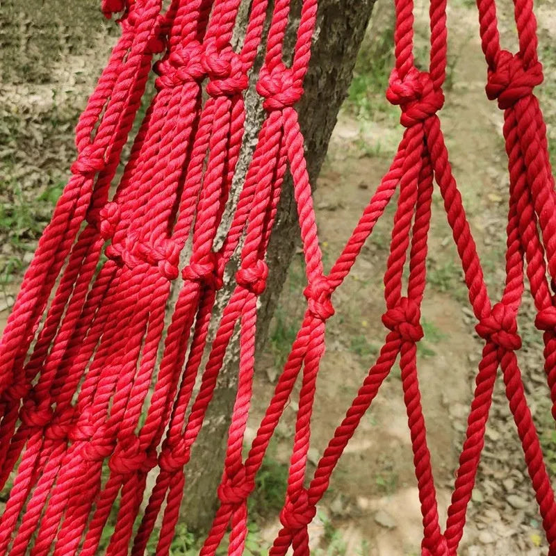 Nylon rope mesh hammock suspended between trees showing mesh pattern and included tying equipment