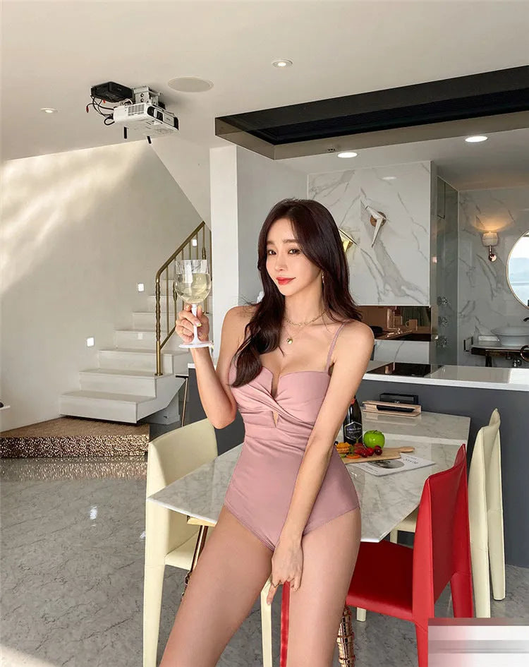 Women's solid colour one-piece swimsuit with spaghetti straps and push-up design in white, pink, or brown.