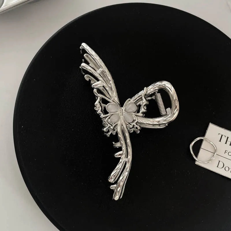 Assortment of silver metal hair claw barrettes with various designs including bows, pearls, and geometric shapes.