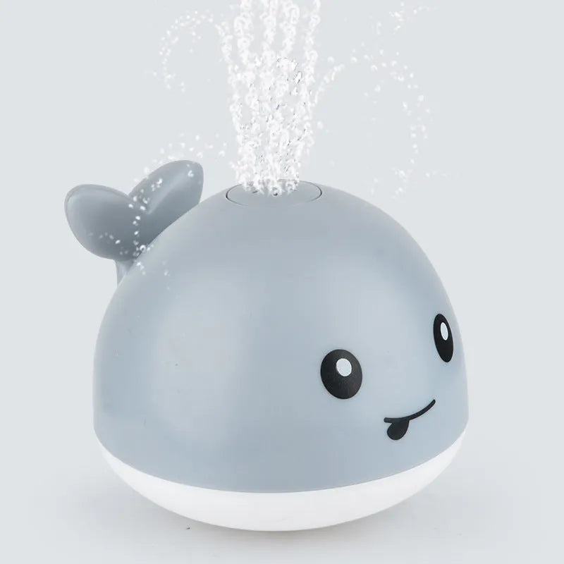 White and blue whale-shaped bath toy with water spray and LED lights floating in water