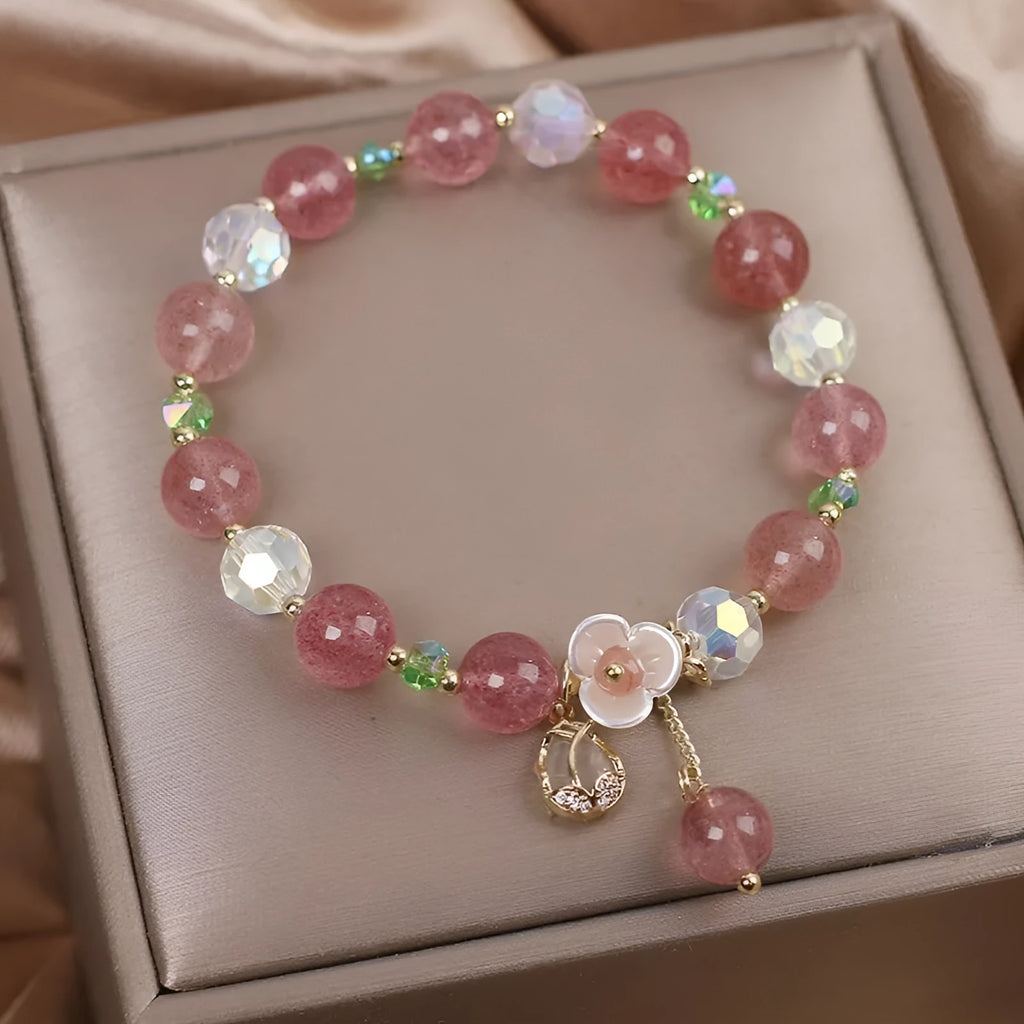 Women's double-layer strawberry quartz crystal bracelet with a red lucky cat charm on a white background.