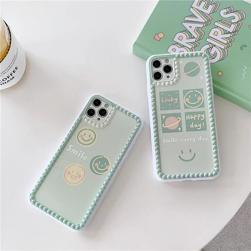 Green TPU iPhone case with geometric smiley face and polka dot frame design on a table.