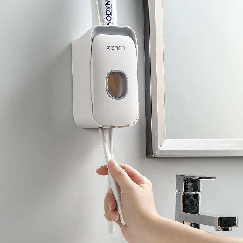Automatic wall-mounted toothpaste dispenser in blue, grey, and pink colours with USB charging cable.