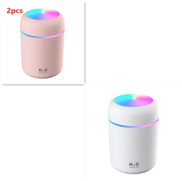 Pink USB desktop humidifier with coloured lights and water tank on a wooden desk