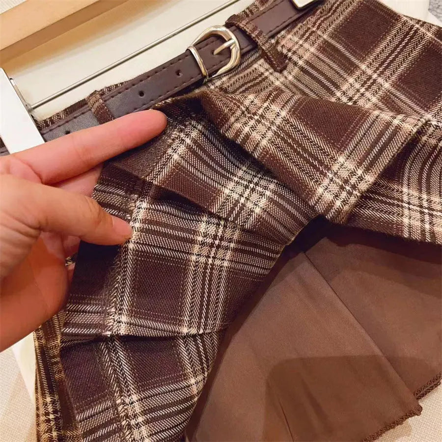 Girls' red and black plaid pleated A-line skirt on a hanger, showing cotton lining.