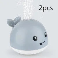 White and blue whale-shaped bath toy with water spray and LED lights floating in water