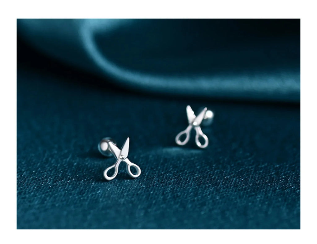 A pair of pure silver screw-style earrings for cartilage piercings with mini scissors screw details.