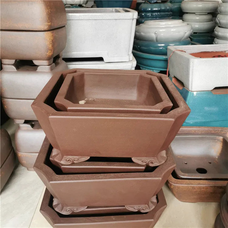 Two brown square stump purple sand flowerpots on a desktop with green plants