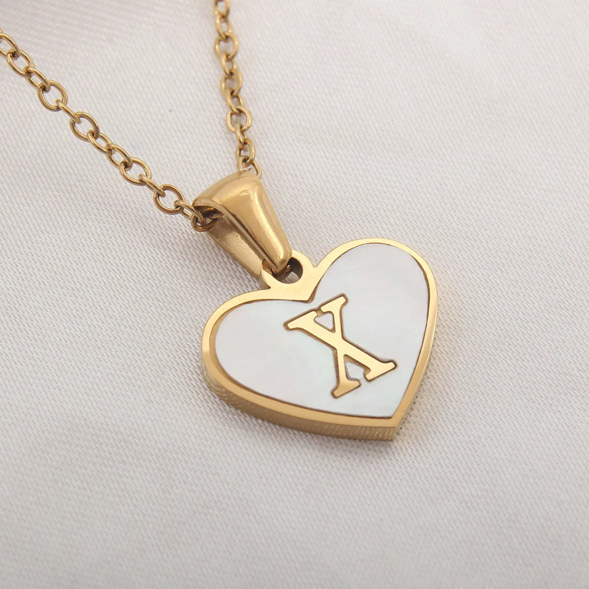 Gold plated heart-shaped white shell pendant personalised initial necklace on a stainless steel chain.