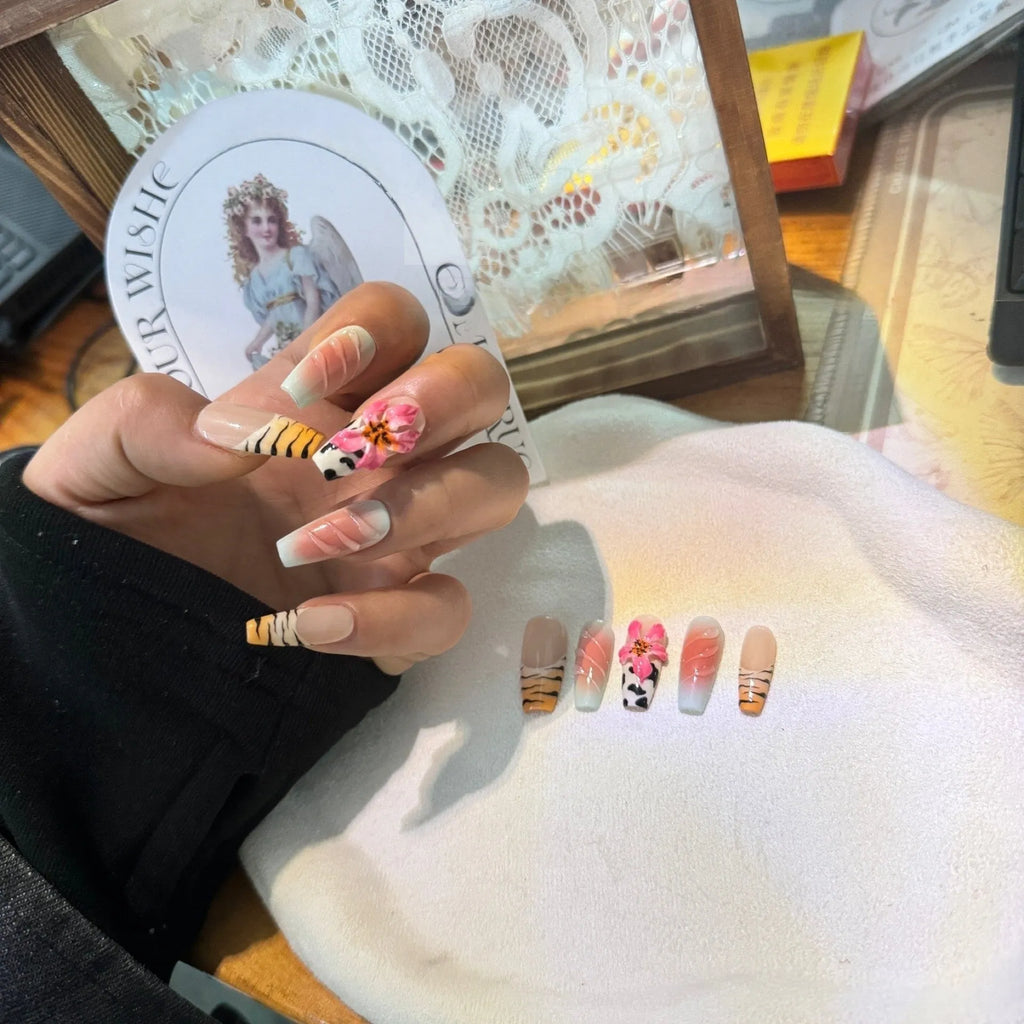 False nails with zebra pattern, carved lily design, and leopard print in long wear-resistant style.