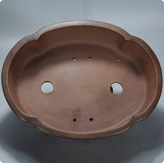 A large, classical-style purple clay flower pot on a wooden floor.
