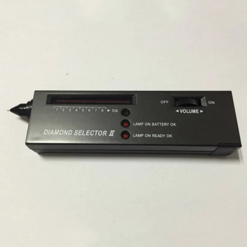 Handheld black diamond thermal conductivity tester with metal probe on a gemstone.