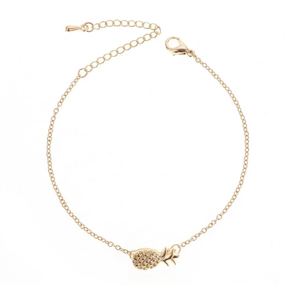 Close-up of a gold-coloured alloy bracelet with a pineapple charm on a simple chain.
