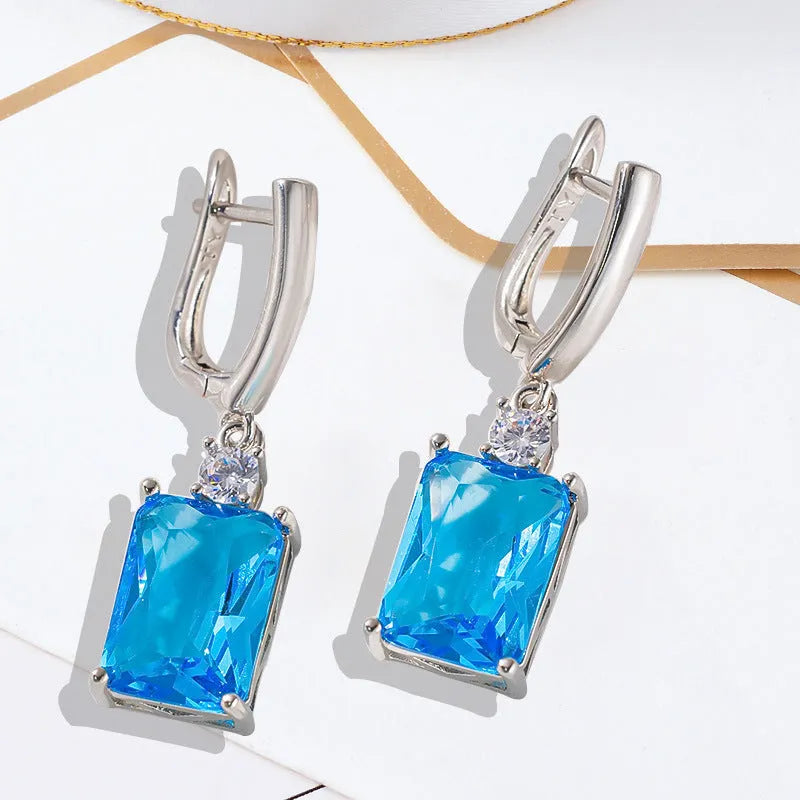A pair of square-shaped gold-coloured geometric earrings on a white background.