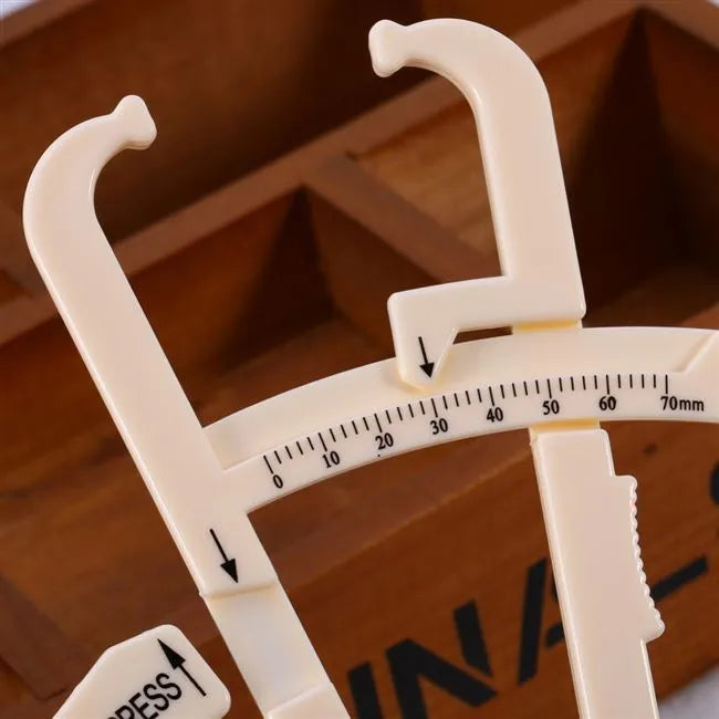 White acrylic body fat caliper with measurement scale for skinfold thickness testing.