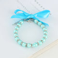 Small dog wearing blue imitation pearl and rhinestone necklace with adjustable clasp and ribbon bow