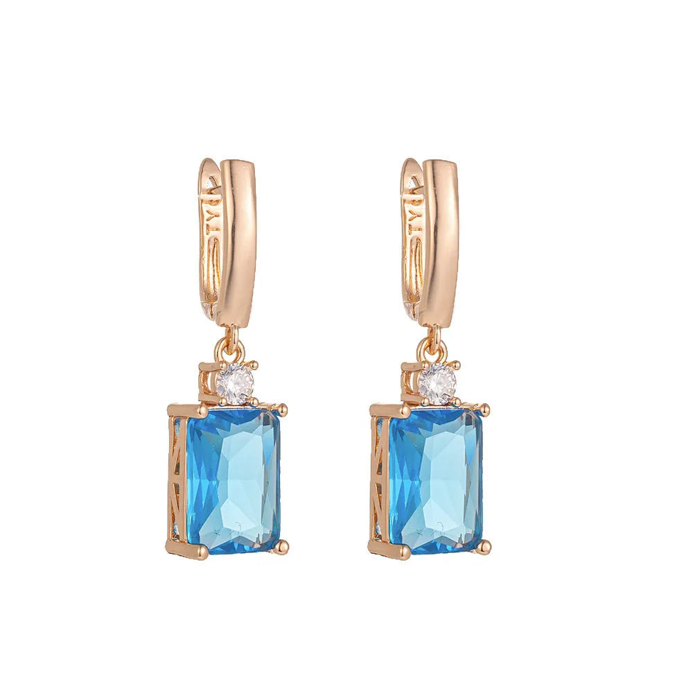 A pair of square-shaped gold-coloured geometric earrings on a white background.