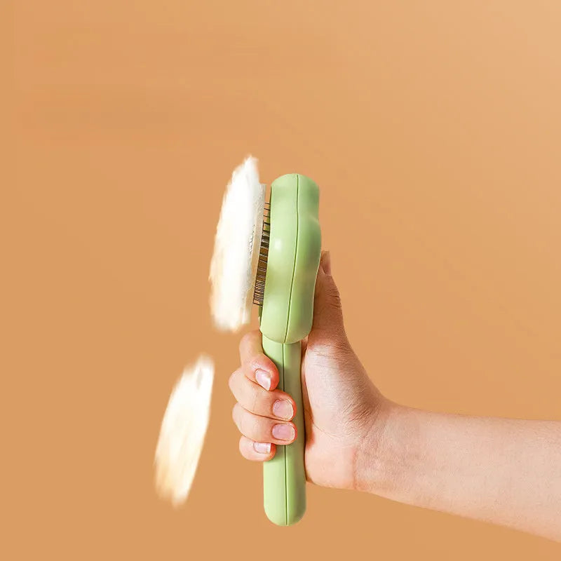 Green self-cleaning cat comb with stainless steel needle pins on a white background