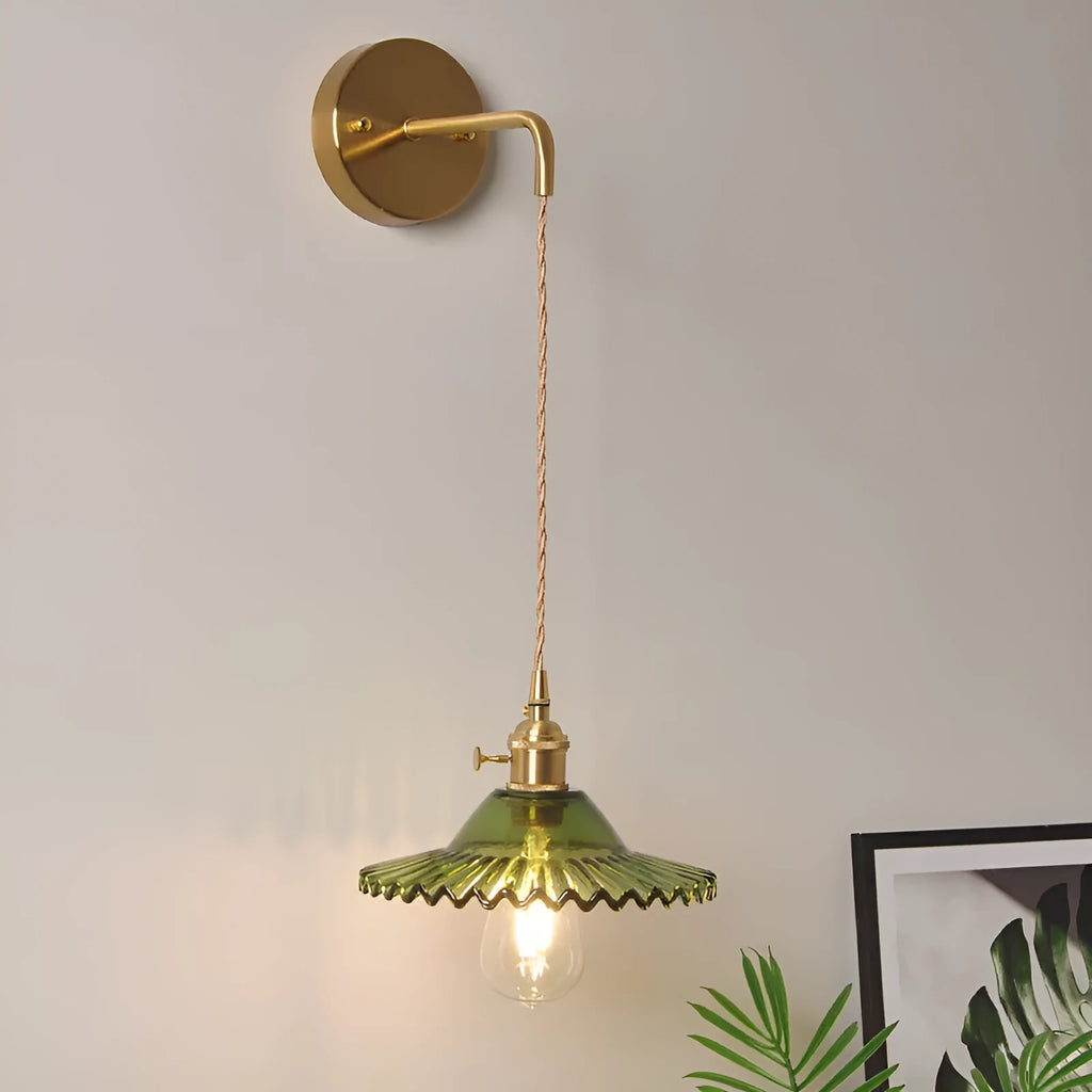 Brass lotus-shaped wall lamp with glass shade in choice of six colours on a plain wall.