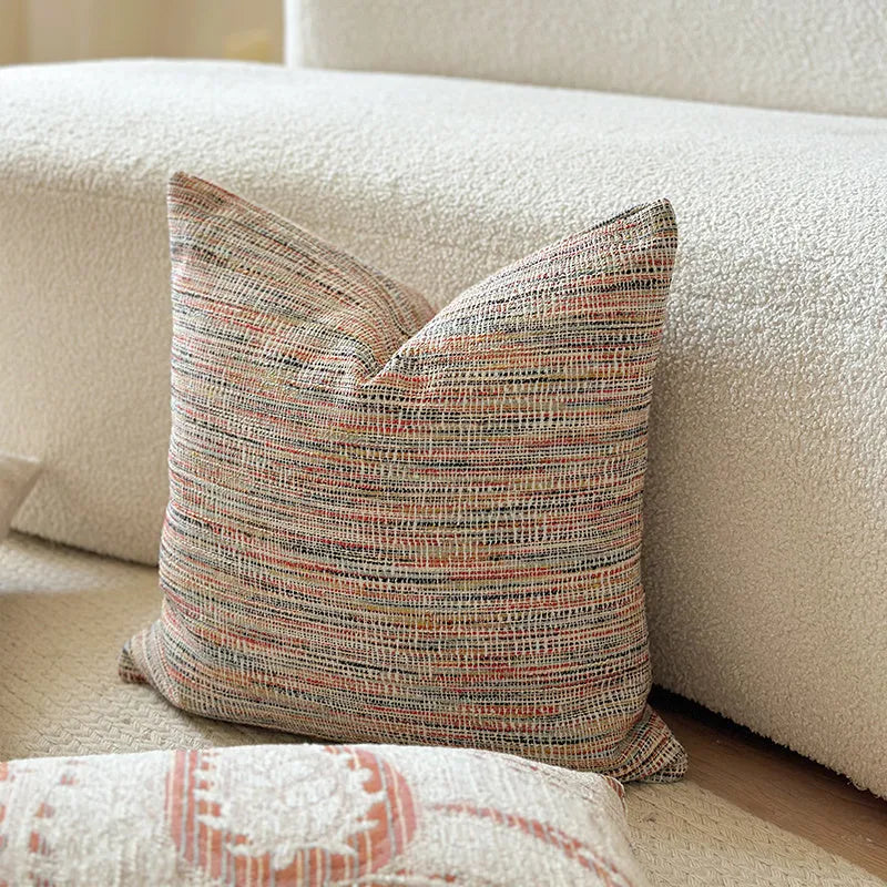 Amber-coloured jacquard pillow cover with paisley and flower pattern, shown in 45x45cm size on a sofa.