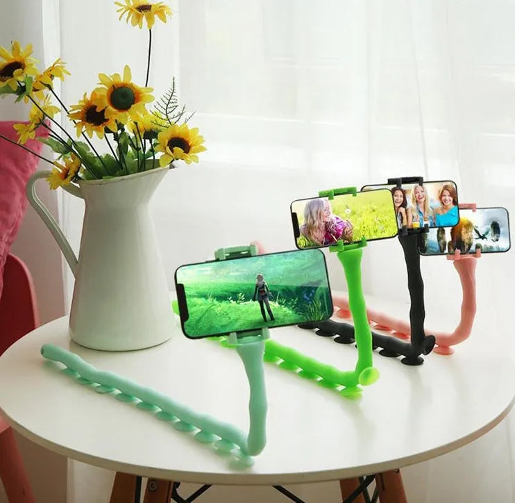 Flexible black suction cup phone holder bent into position on a desktop
