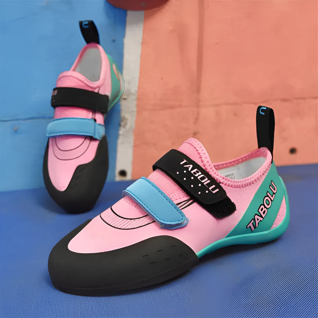 Pair of beginner rock climbing shoes with Velcro strap and black and red rubber outsole.